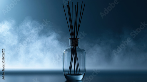A glass vase holds several sticks used for scent. The setting is dark with smoke in the air. This scene shows an indoor space that creates an atmosphere