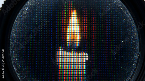 Extreme macro of pixels forming a candle flame on a digital screen through a lens.