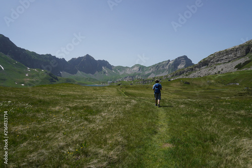 Hiker walking through Alpine valley in Melchsee‑Frutt, Switzerland.