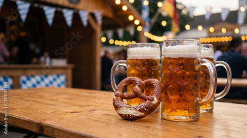Beer mugs and pretzel on table at outdoor Oktoberfest celebration
