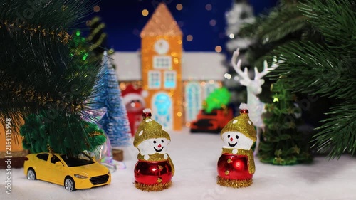 Two snowmen with a car against the backdrop of a chapel with a car and a snowman