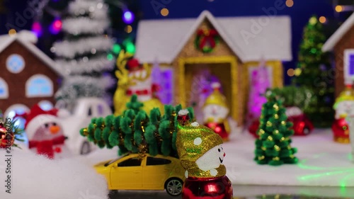 A beautiful Christmas town with a yellow car and a snowman with an unusual Santa Claus in the foreground