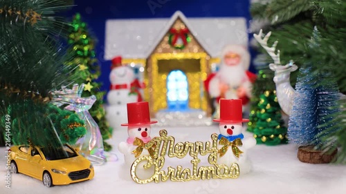 Two snowmen with letters among Christmas trees against the backdrop of a house with Santa Claus and a snowman