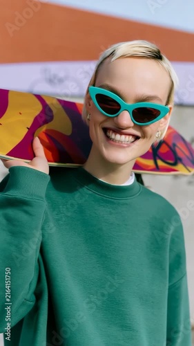 Smiling skateboarder with teal sunglasses and green sweatshirt at urban skatepark for lifestyle portrait background and banner design