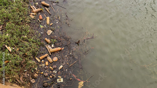 Cuadro en lienzo A polluted lakeshore with plastic bottles and household waste accumulated at the water's edge
