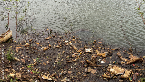 Cuadro en lienzo A polluted lakeshore with a large amount of plastic bottles, packaging, and household trash