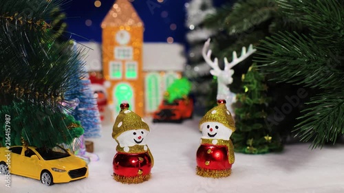 Two snowmen with a car against the backdrop of a chapel with a car and a snowman