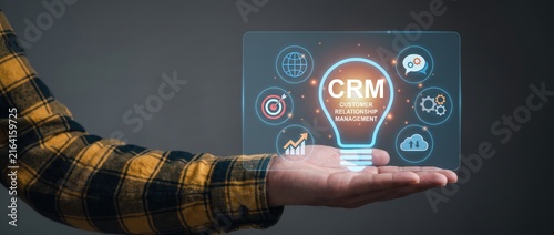 Futuristic technology idea featuring a hand grasping a clear screen that showcases crm (customer relationship management) icons alongside a creative lightbulb graphic
