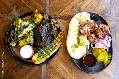 Fresh kebab with pita bread, onions, pickles, roasted vegetables and sauces on the table in a restaurant.