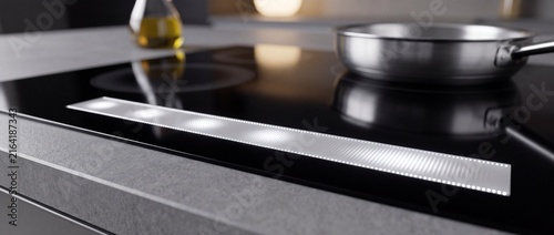 Contemporary induction kitchen hob featuring minimalist haptic light bar touch control interface on dark polished stone surface counter