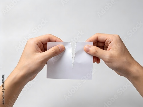 Hands tearing a blank piece of white paper in half