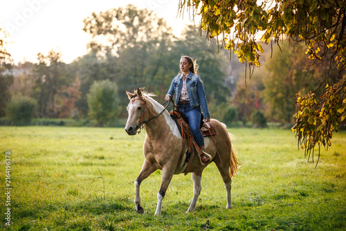 Quadro su tela Woman riding horse at meadow