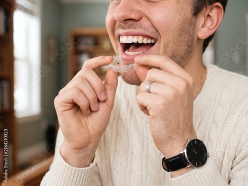 Man inserting a clear dental aligner into his mouth