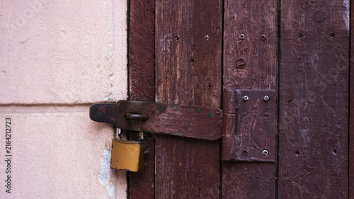 Obraz na plátně Old brown wooden door locked with a metal padlock on a rusty latch