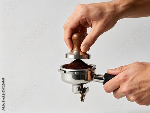 Barista hands using a tamper to press coffee in a portafilter