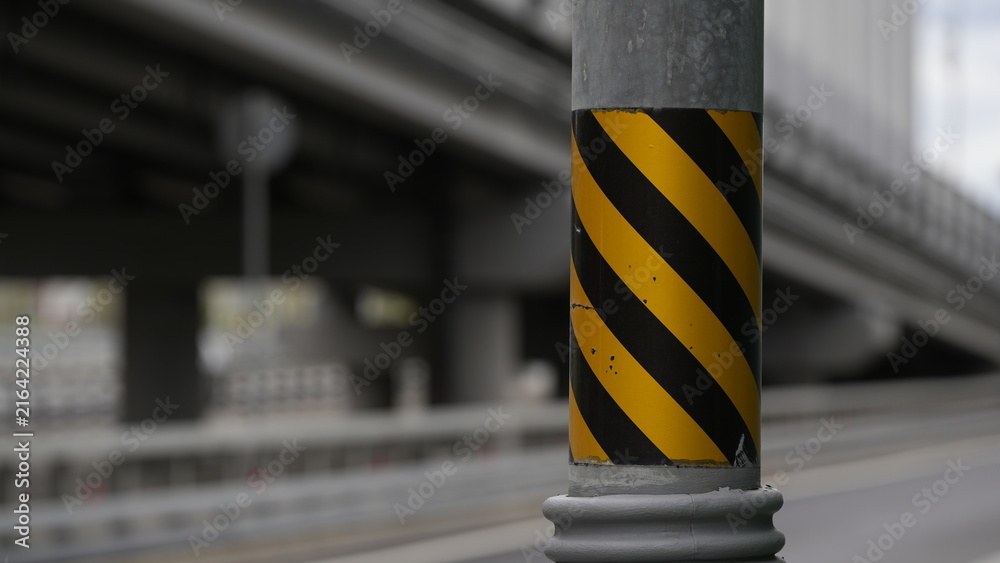Naklejka premium Yellow and black safety marked support column on a modern bridge, highlighting transportation infrastructure, urban engineering, construction design and traffic safety elements