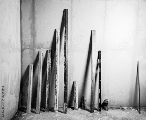 a set of aluminum building plastering rules of different sizes and the building level of the plastered wall black and white photo