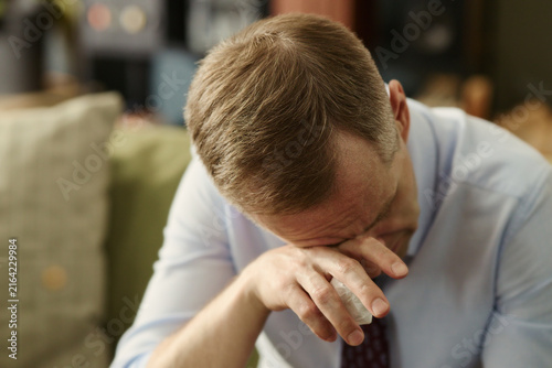 Photography Middle aged Caucasian man crying and wiping tears with tissue, experiencing emotional breakdown
