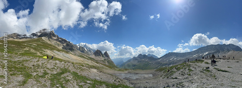 Obraz na plátně Alpine mountain pass panoramic view rocky peaks glacier green slopes hikers grou