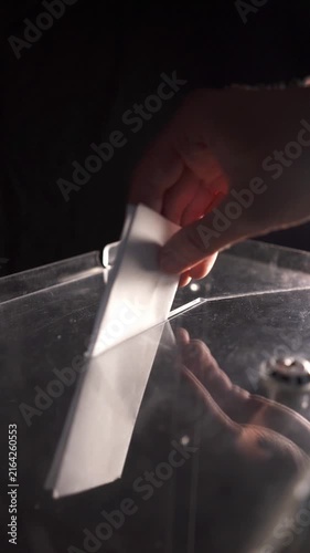 Voter holding ballot sheet above transparent box slot during global or US elections