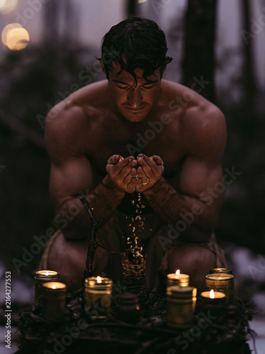 Man Performing Candle Ritual with Cupped Hands in Forest