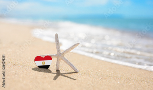 Fotografía Starfish and Egypt flag on sandy beach.