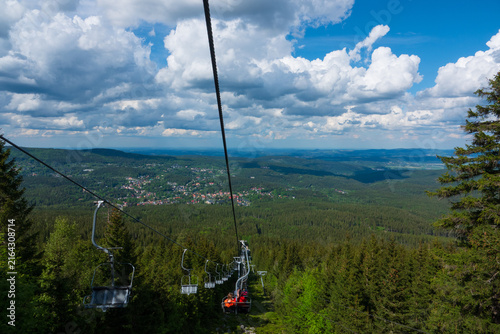 Chairlift moving over green forest with a town view in Giant Mountains. Szklarska Poreba, Poland
