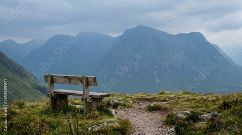 Infinite Contemplation - Solitary weathered wooden bench facing a colossal, unlabelled mountain range in heavy blue-grey haze