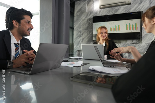 Konstfotografi Hand stretched across the table, the young analyst presses her point as the manager chuckles behind his laptop in the sunlit meeting room in a bright modern coworking office
