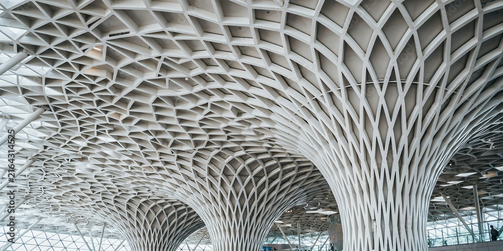Fototapeta premium Modern architectural ceiling with intricate geometric lattice structure and tree columns.