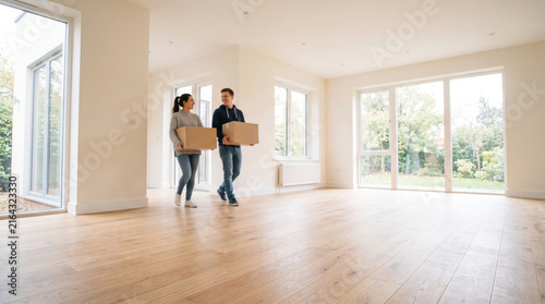 Happy couple moving into a new empty house holding cardboard boxes, perfect for corporate strategies, business models, and innovative marketing ads