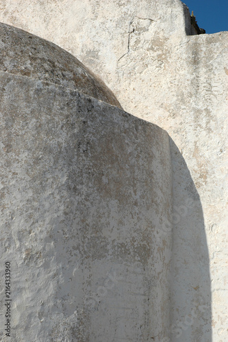 Close up view of the traditional weathered white plaster apse and textured exterior walls of the historic Church of Panagia Myrtidiotissa on Kythira island