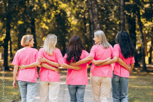 Obraz na plátně Back view diverse group of multinational women wearing stylish pink t shirts hug