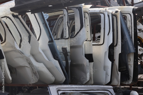 Row of White Disassembled Car Doors Stacked in an Auto Junkyard