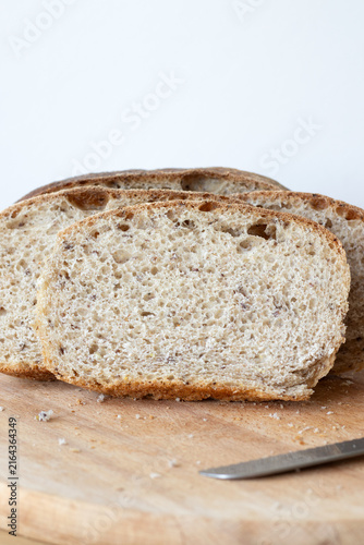 Homemade brown bread slices on a cutting board with white background. Copy space.