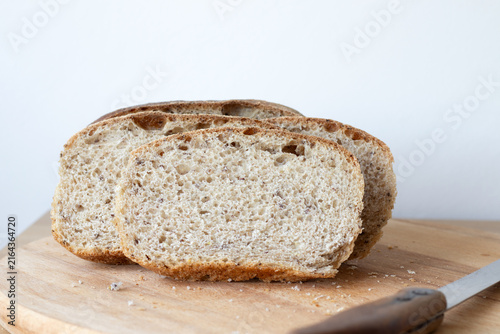 Homemade bread slices on a cutting board with white background. Copy space.