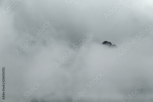 Cuadro en lienzo Minimalist Silhouette of a Mountain Peak in Dense White Fog