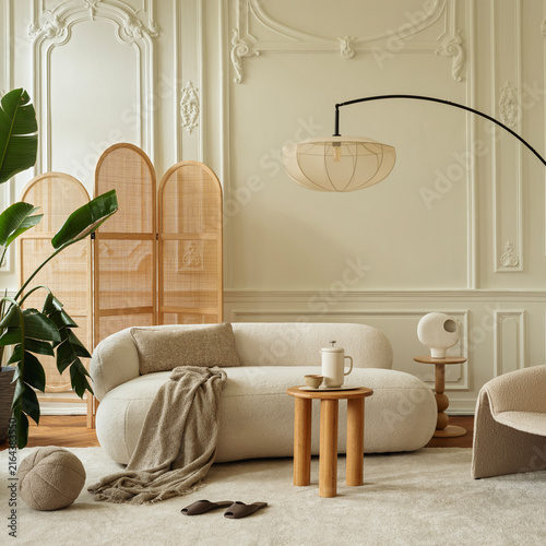 Elegant and cozy modern living room interior design with neutral cream color palette, comfortable curved sofa, stylish furniture, and warm lighting