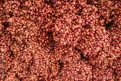 Fresh red shallots tied in dense bunches create a textured, colorful display at a market stall, evoking harvest, culinary ingredients, rustic produce and natural farm-to-table cooking supplies.