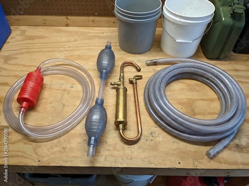 Manual Fluid Transfer Equipment and Siphon Pumps with Hoses on a Wooden Workbench
