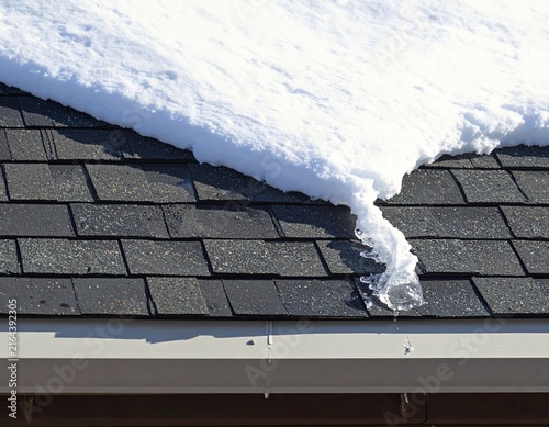 Thick snow layer resting across weathered residential roof shingles