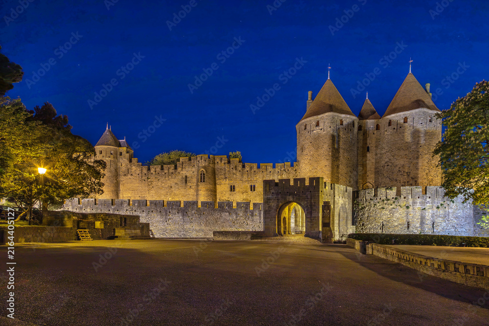 Fototapeta premium Evening view of Cite de Carcassonne in France, showing the illuminated main entrance. Medieval fortress architecture at dusk