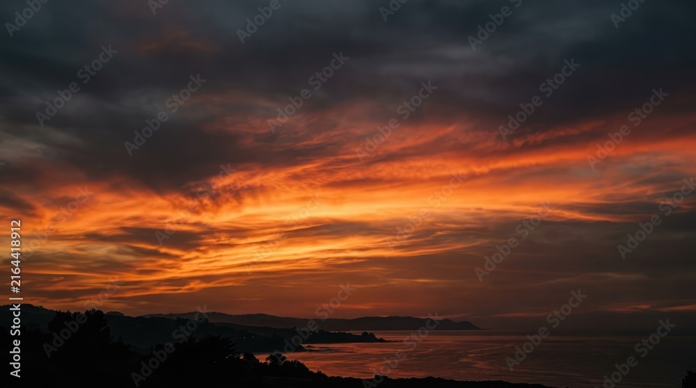 Fototapeta premium Dramatic fiery sunset over ocean waves with dark stormy sky above