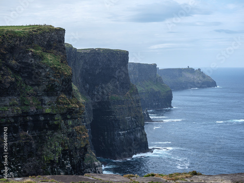 Fotografie Mossy cliffs rise steeply from churning sea