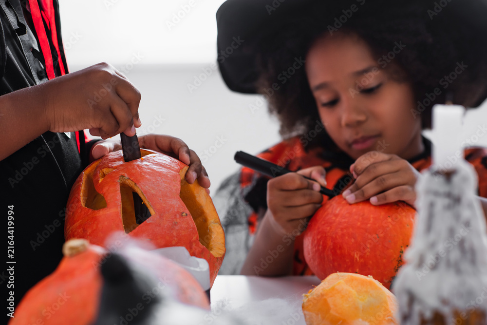 Fototapeta premium Halloween fun with kids carving pumpkins in a cozy autumn setting