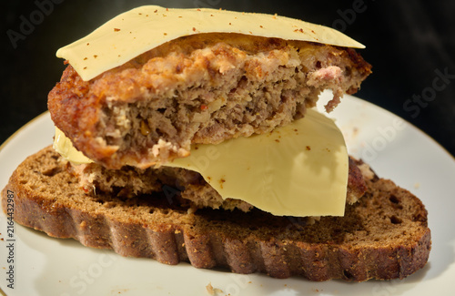 Photography easy to make sandwich made of black bread, a patty and processed cheese on a black background