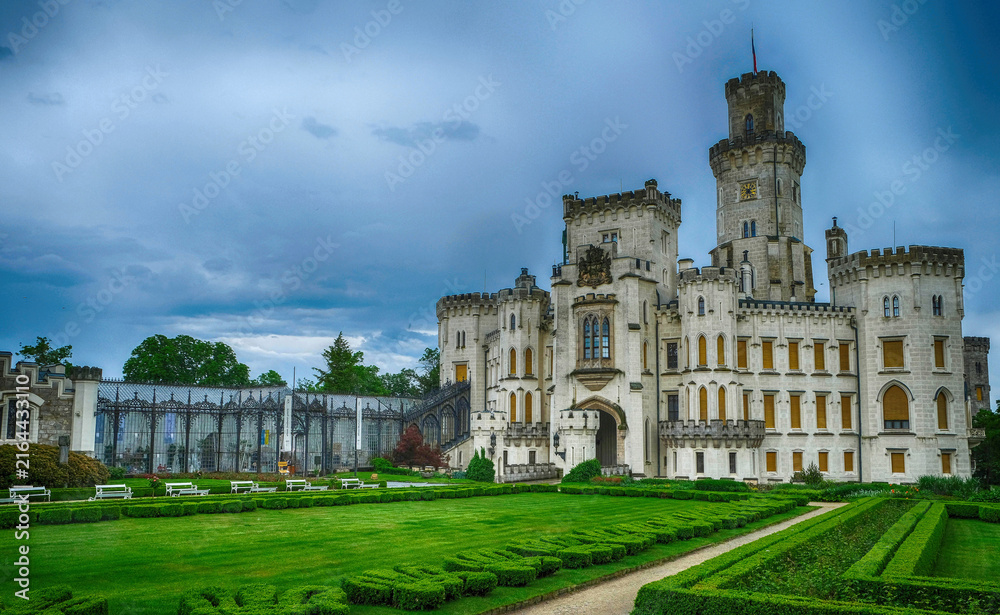 Fototapeta premium Professional architecture photography of Hluboka nad Vltavou castle front view with formal park. Famous romantic landmark building under storm sky for travel guide catalog.
