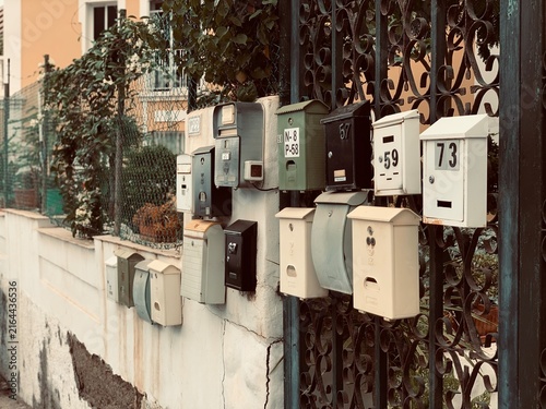 Collection of Vintage Mailboxes Mounted on Wrought Iron Gate and Wall