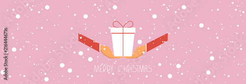 Minimalistic flat vector illustration of a Christmas horizontal banner in soft pink color. Image of two human hands carefully holding a white gift box with a red ribbon pattern, surrounded by a magica
