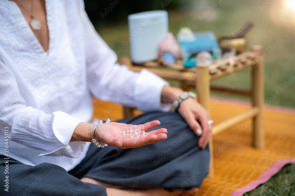 Fototapeta premium Woman holding a clear crystal during a mindfulness session with a Schumann wave generator, symbolizing emotional clarity, grounding, spiritual connection, and holistic wellness.